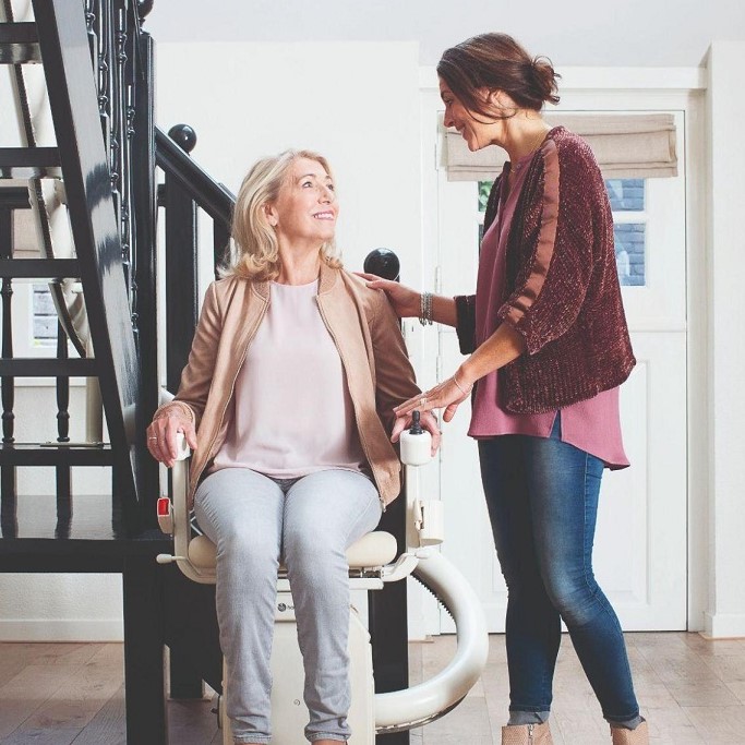 Lady Assisting Someone Riding a Curved Stairlift